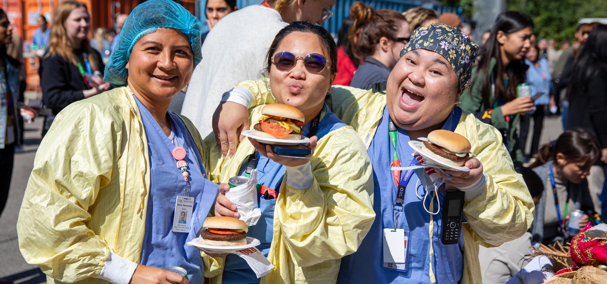 Sinai Health staff members wearing scrubs and holding burgers on paper plates at the staff appreciation bbq