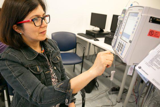 A woman looking at a piece of medical equipment.