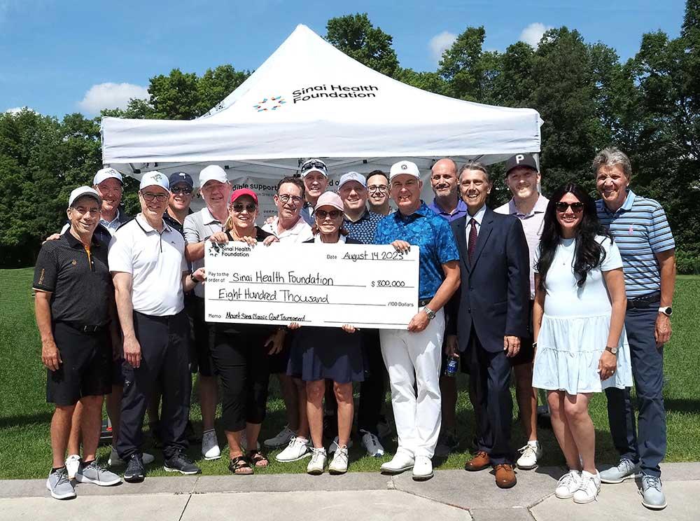 Group of people stand outside holding presentation cheque