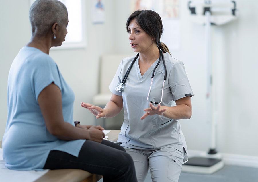 medical professional speaks to a patient sitting on an examination table