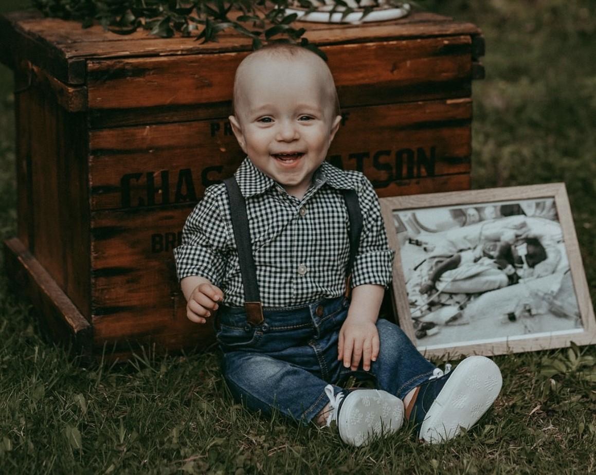 Little boy sits next to black and white photo