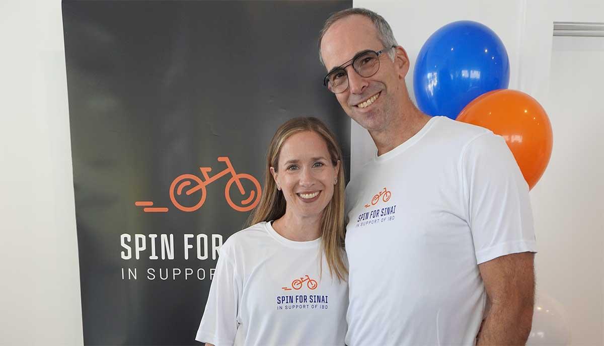 man and woman stand in front of banner and balloons 