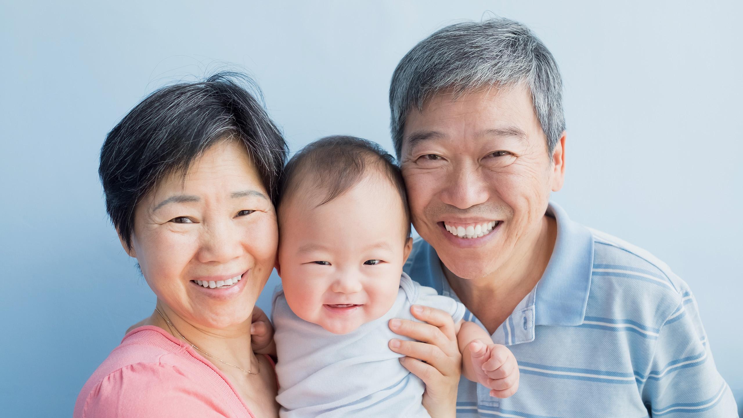 Grandparents holding grandchild and smiling