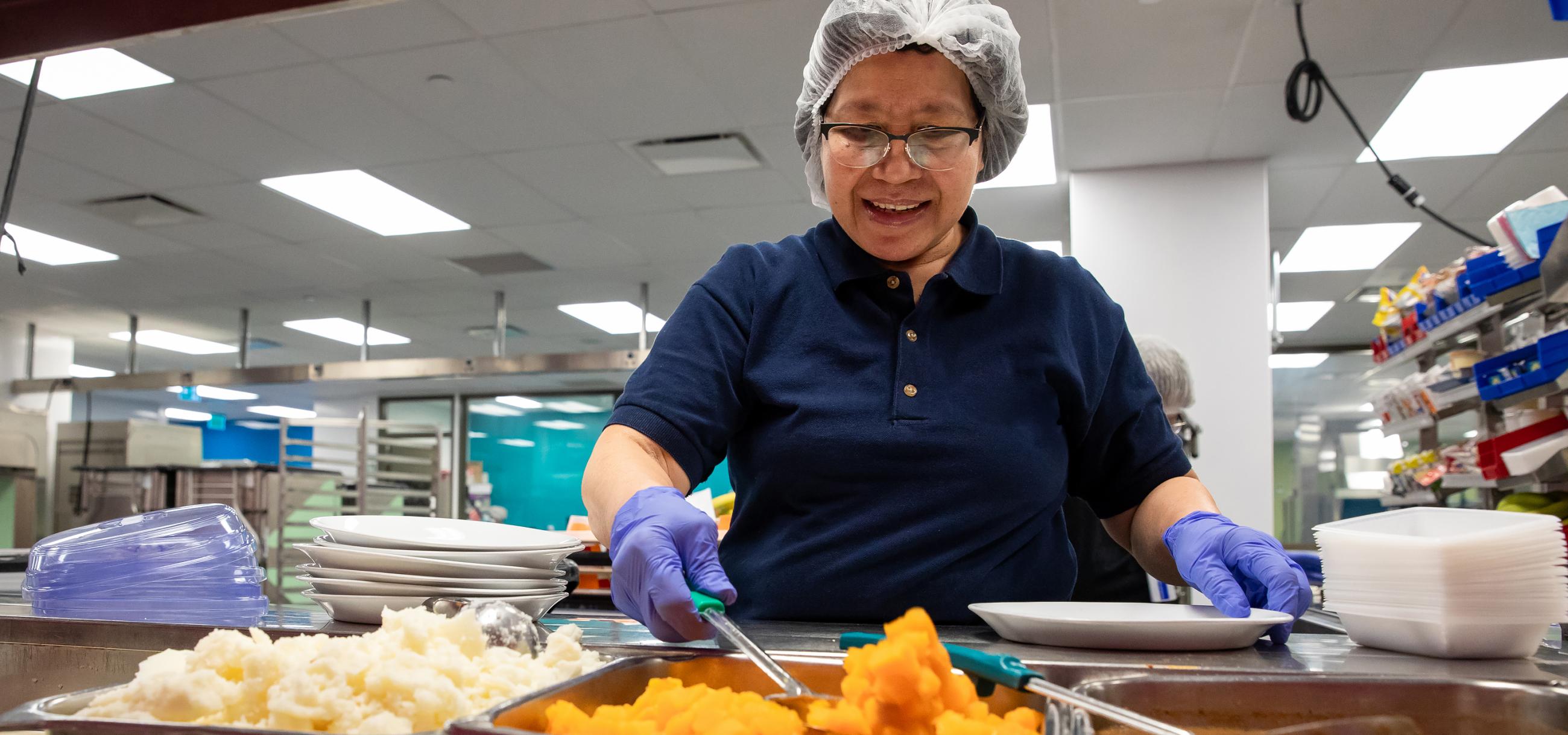 Staff member at Mount Sinai Hospital in the new revamped kitchen. The staff member is serving food 