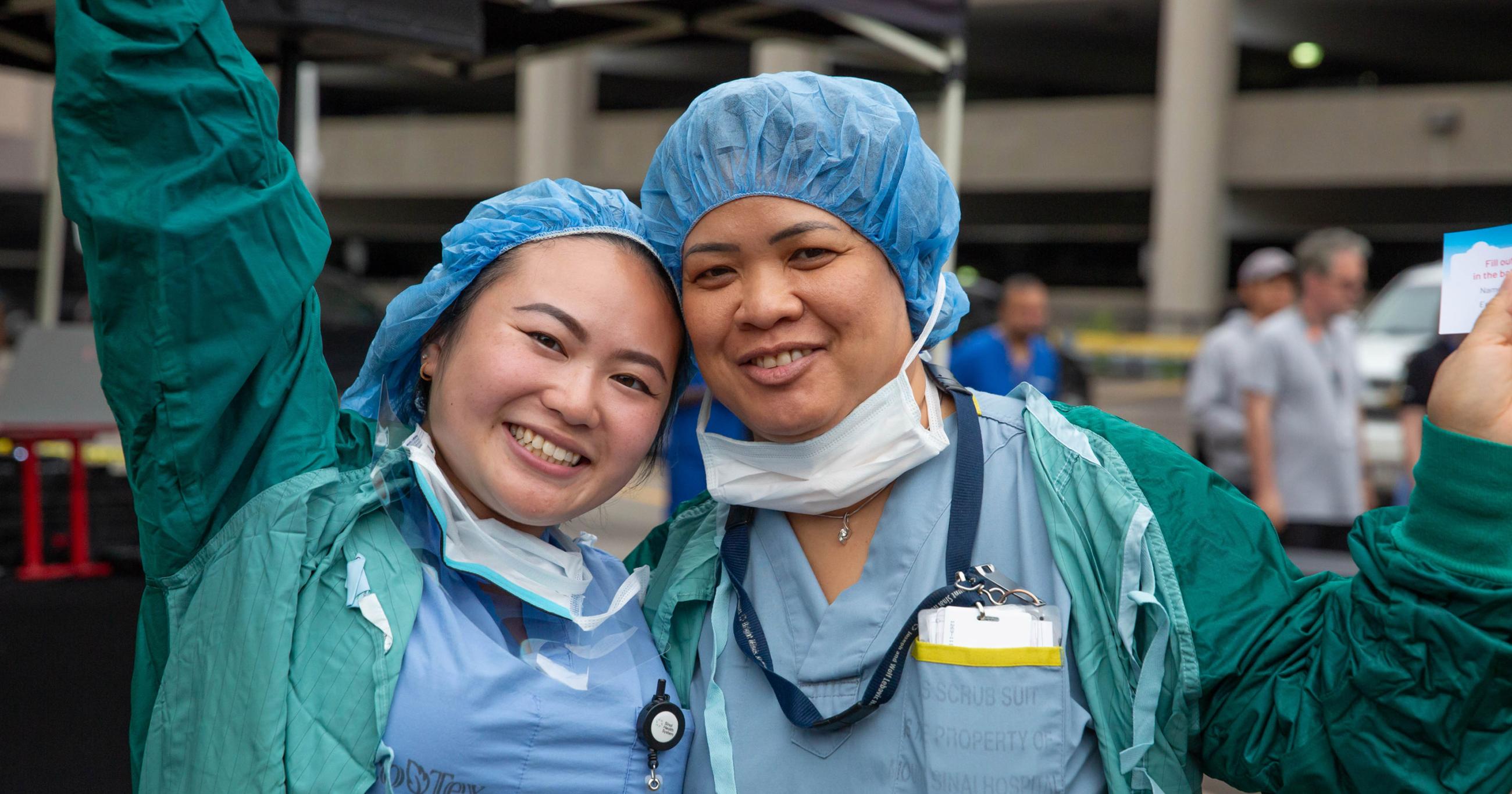 Two smiling people in scrubs outdoors