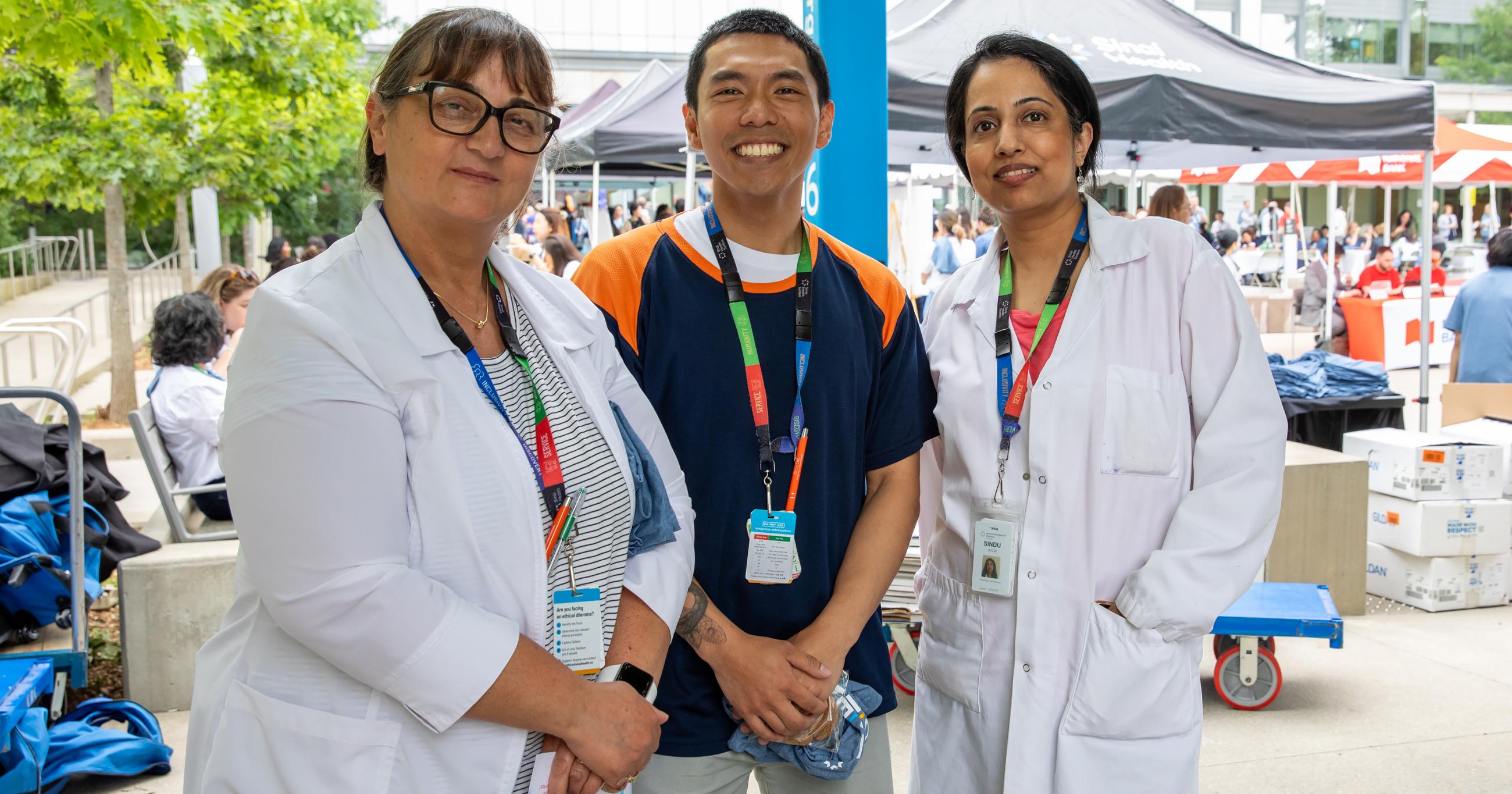 Three employees smiling outdoors