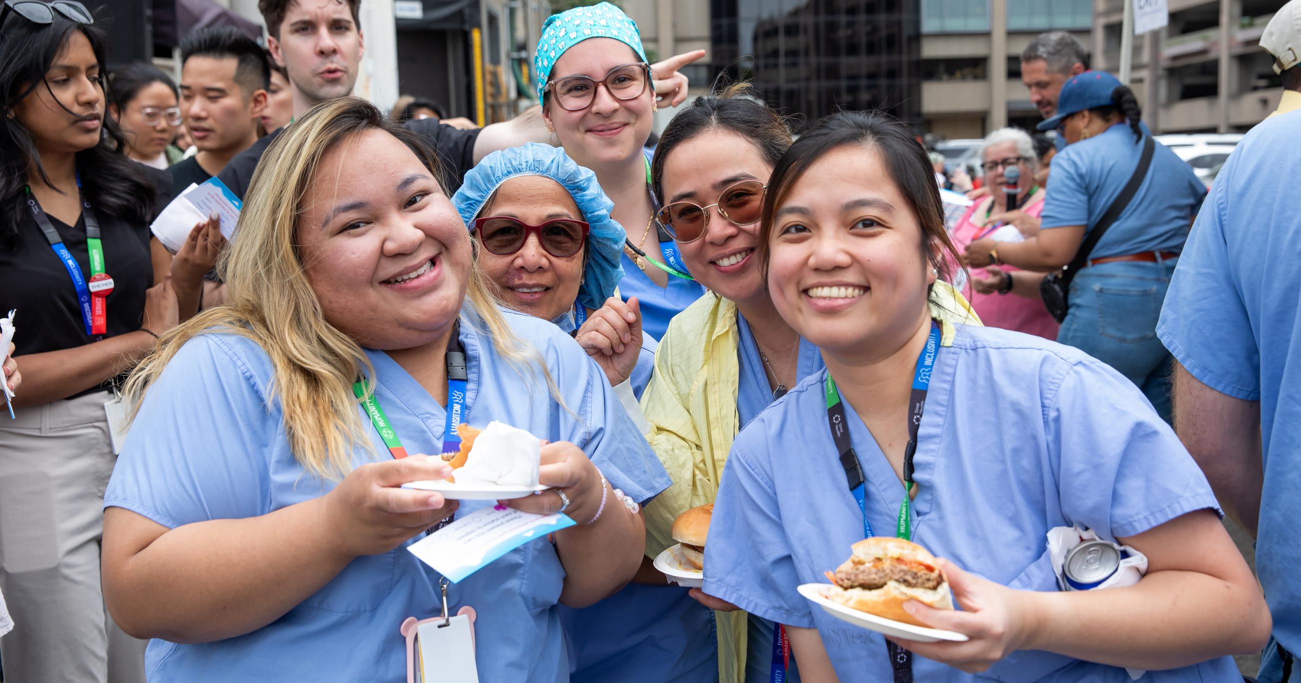 employees in scrubs smiling holding food