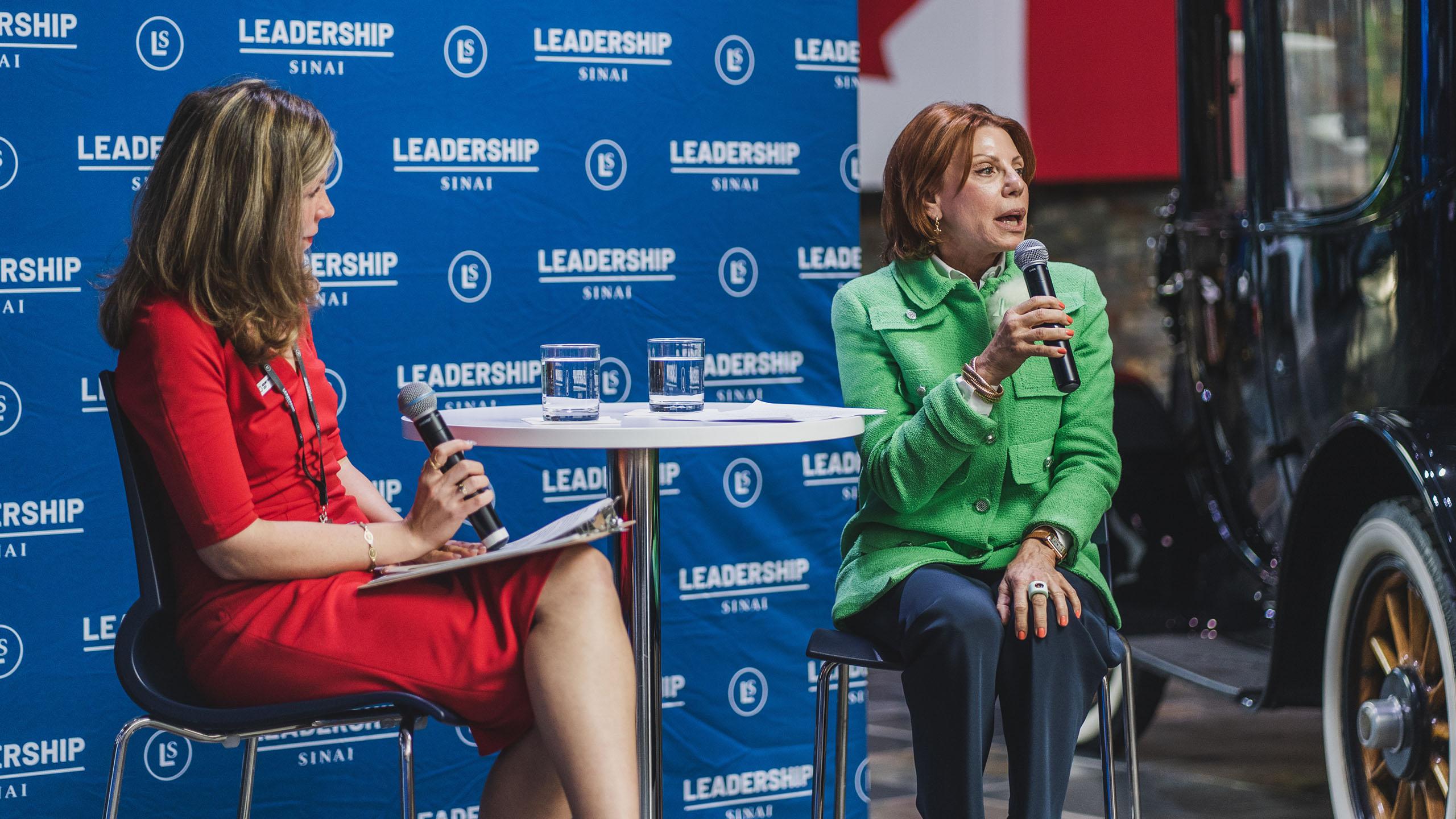 Two women which microphone speaking at a table