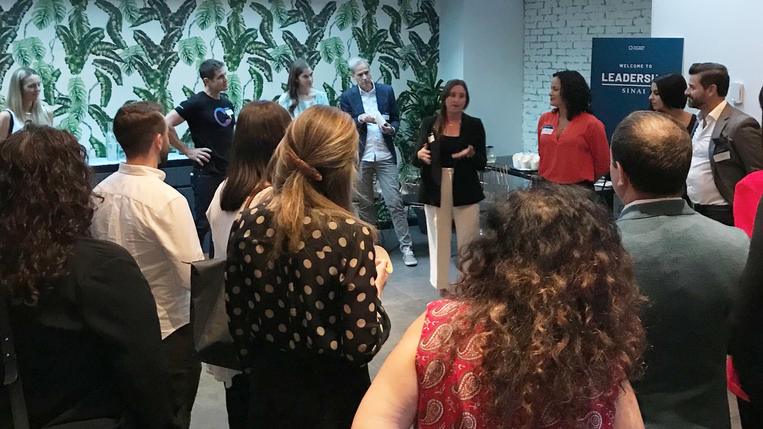 Group of people standing and watching a woman give a lecture