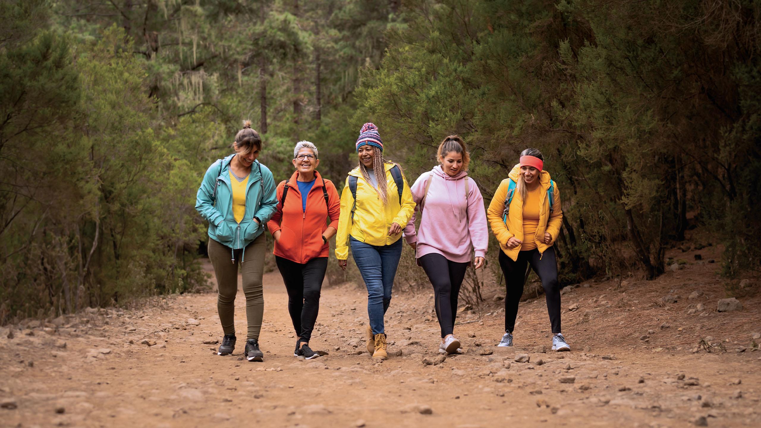 Five women walking in a wooded area