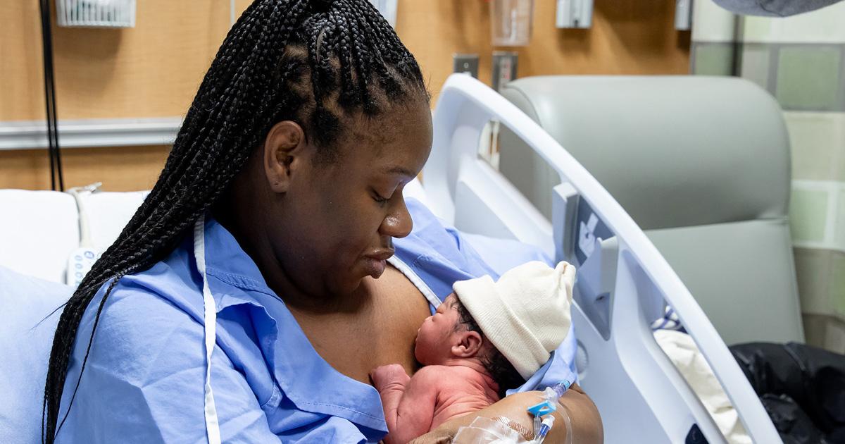 New mother holding her baby in a hospital bed.