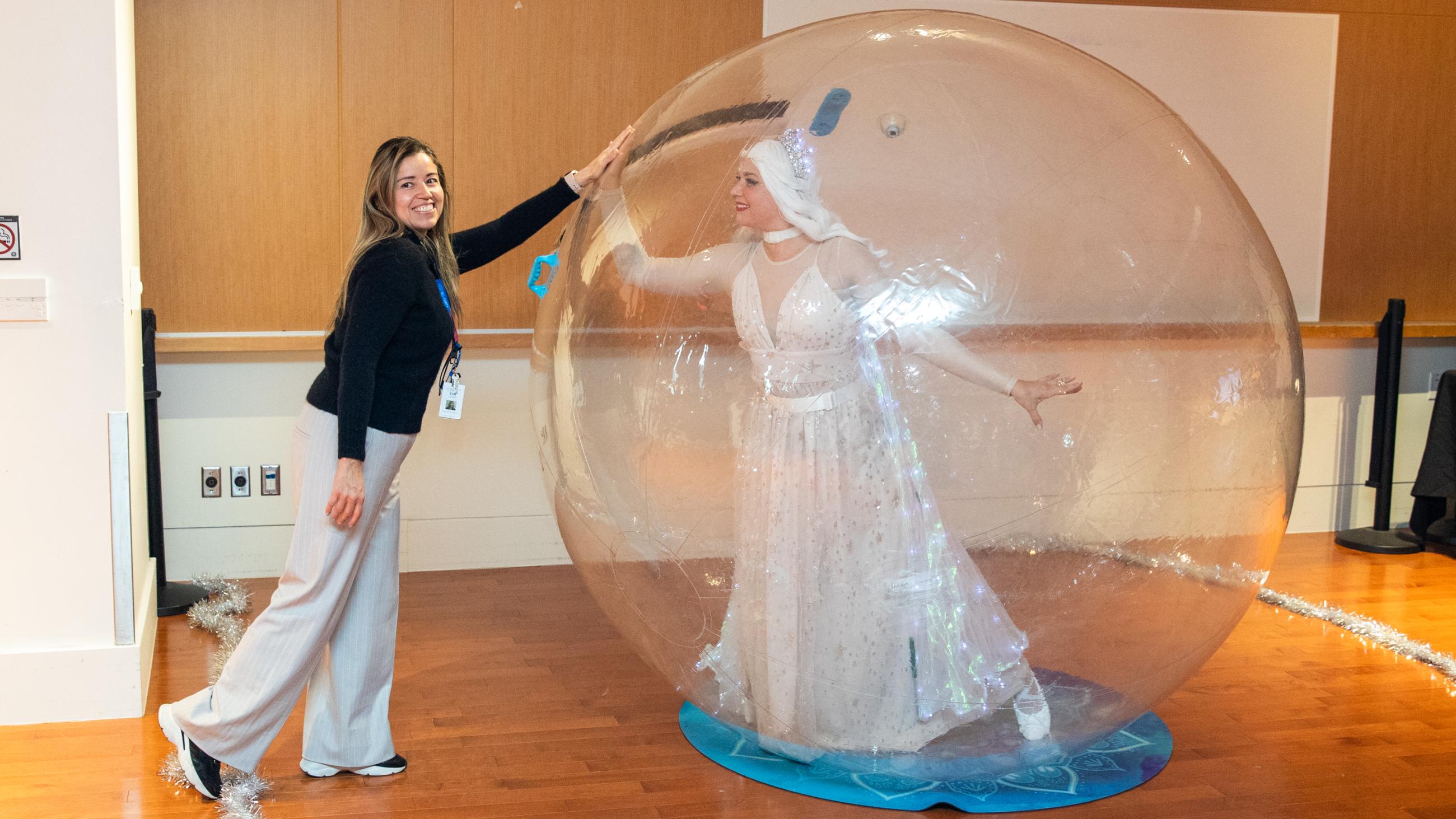 A staff member poses next to a performer inside an inflatable snow globe during Sinai Health’s Holiday Open House. 