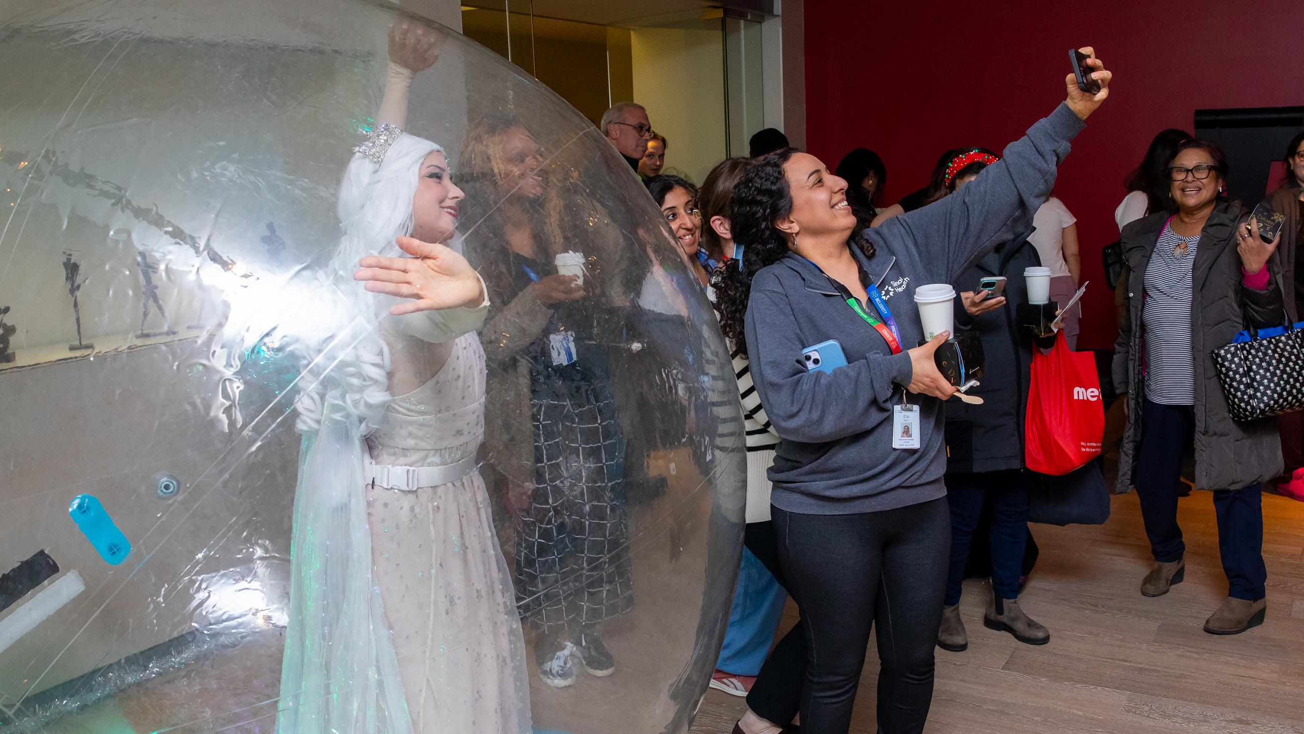 Staff members pose next to a performer inside an inflatable snow globe during Sinai Health’s Holiday Open House.