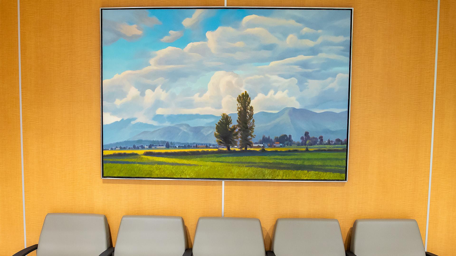 A painting sits above chairs in Sinai Health’s Cancer Care Clinic, depicting a mountain range with trees and a blue sky.