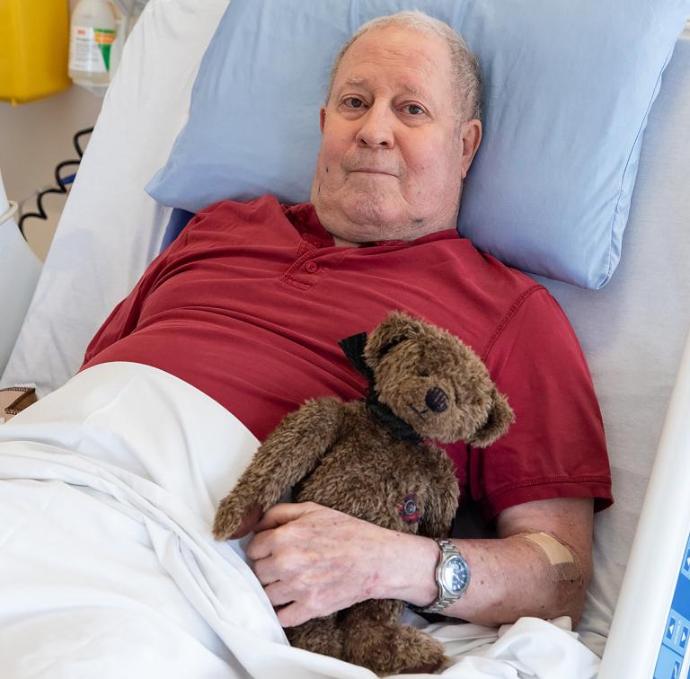 A palliative care patient holding a teddy bear