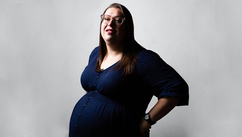 a bespectacled and visibly pregnant woman