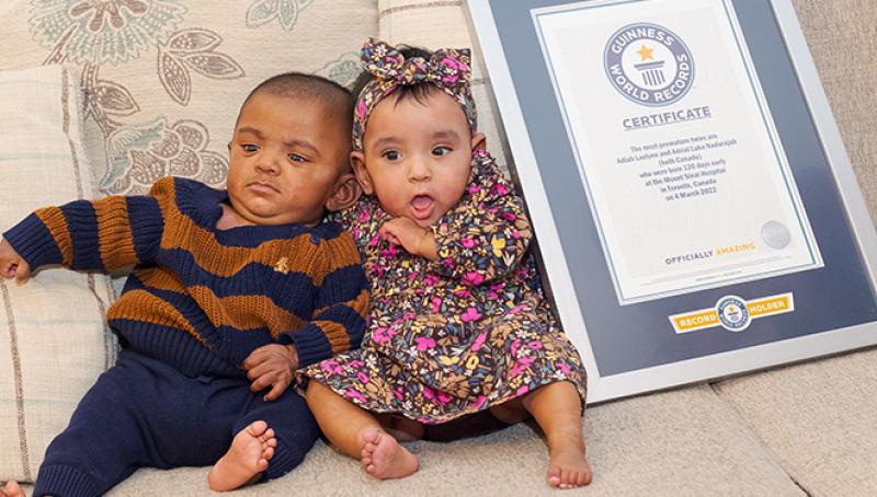 The world’s most premature twins sitting on a sofa next to their Guinness Record Certificate