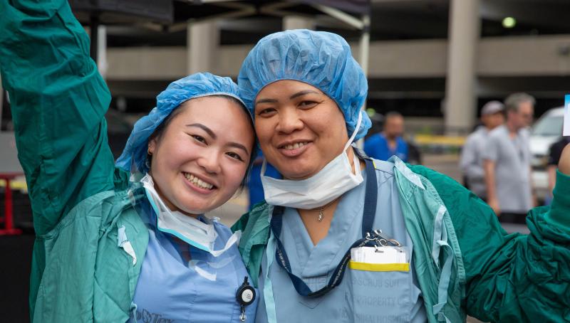 Two smiling people in scrubs outdoors