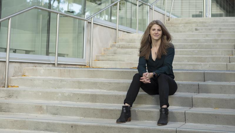 Woman sitting on the steps outside a glass-walled building