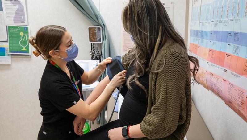 A visibly pregnant woman receiving care from a health-care professional