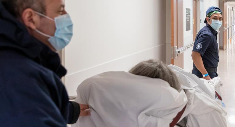 Two people transport a patient down a hallway at Bridgepoint Active Healthcare.