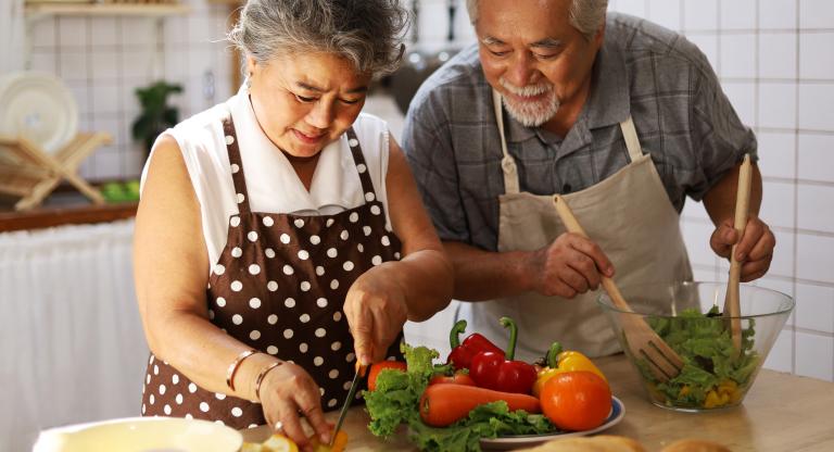 couple making salad in kitchen