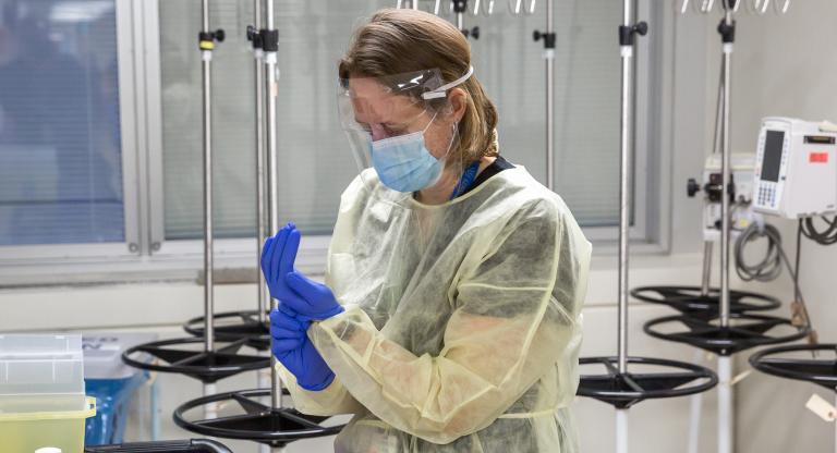 Dr. Erin Bearss dons personal protective equipment to administer the COVID-19 vaccine.