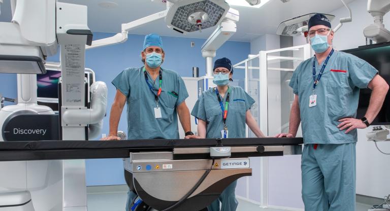 Three surgeons posing by an operating table