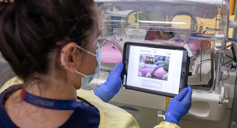 Woman with a tablet device in front of a premature baby at Mount Sinai Hospital