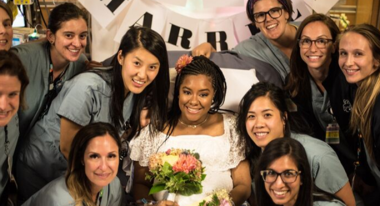 Nurses with patient in wedding dress and bouquet of flowers. 