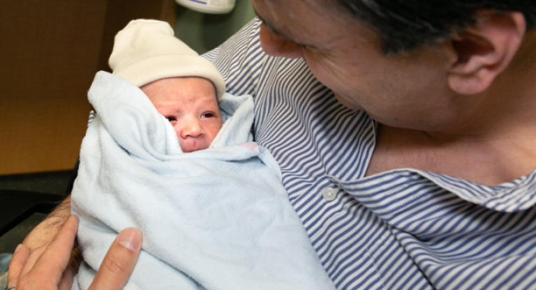 Father holding preterm baby in the neonatal intensive care unit