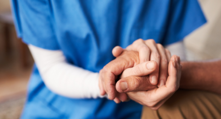 Health care working holding a patient's hand