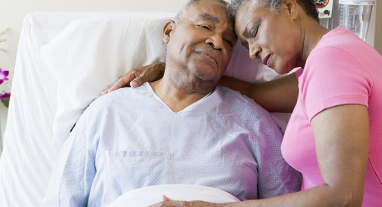 Woman comforting man in hospital bed