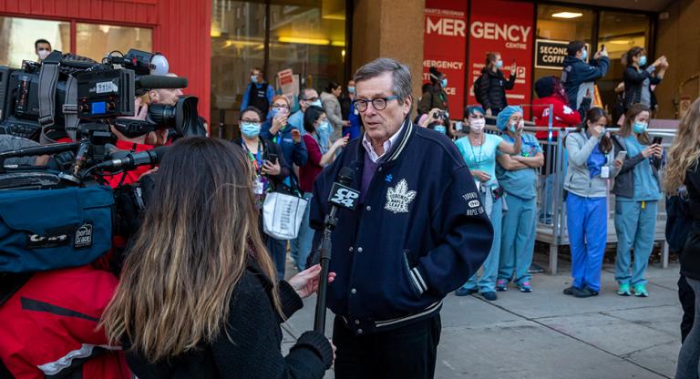 Toronto Mayor John Tory speaks with the media outside Mount Sinai Hospital's emergency department. Health-care workers stand in the background.