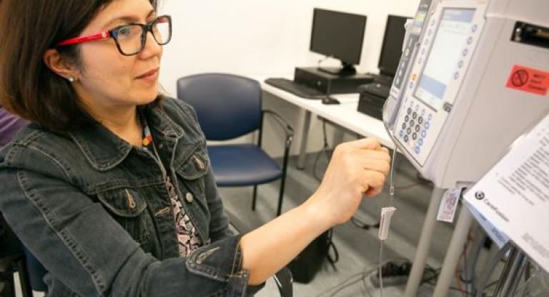 A woman looking at a piece of medical equipment.