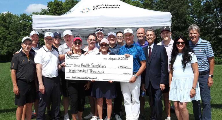 Group of people stand outside holding presentation cheque