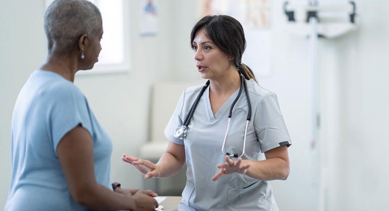 medical professional speaks to a patient sitting on an examination table