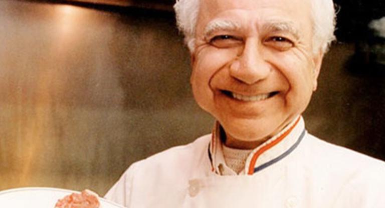 Man wearing chef jacket, holding a steak