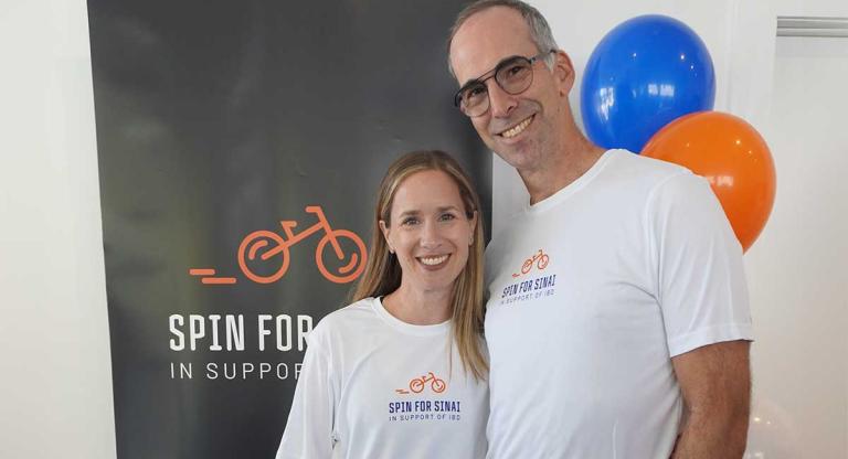 man and woman stand in front of banner and balloons 