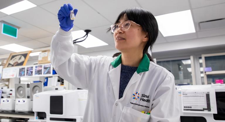 Female lab researcher looking at test tube