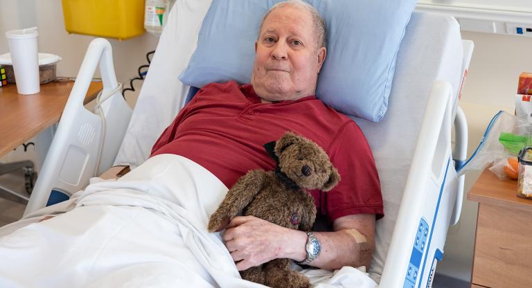 A palliative care patient holding a teddy bear