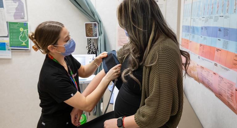 A visibly pregnant woman receiving care from a health-care professional