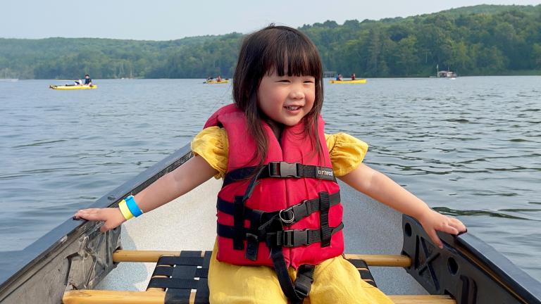 Child on a canoe wearing a safety jacket