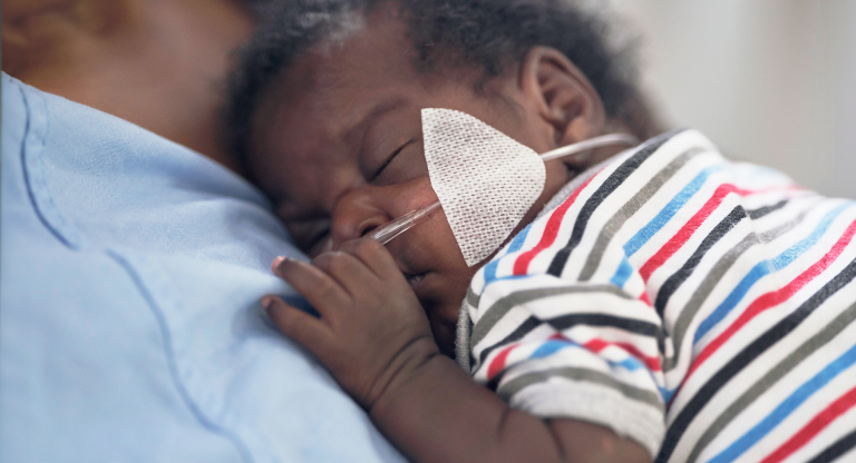 Baby in striped shirt sleeping on mother