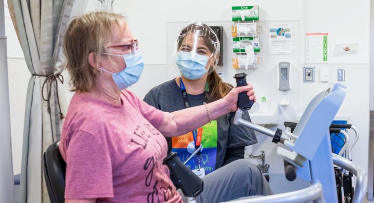 Medical professional assisting a rehabilitation patient on an reclining exercise bike