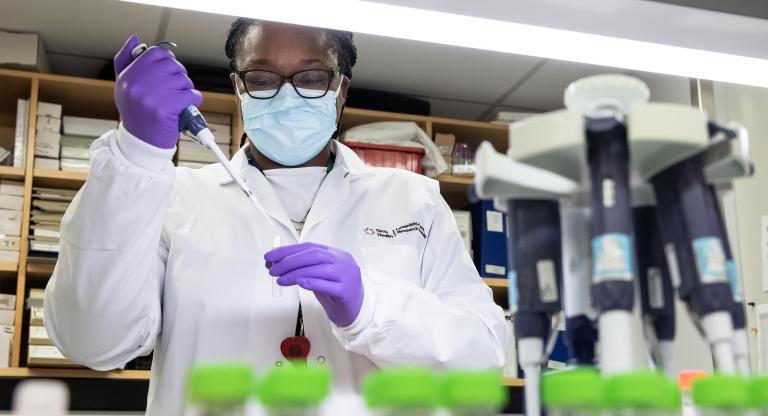 Researcher in a laboratory filling a test tube with liquid dropper