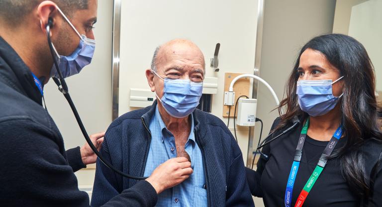 two doctors treating an older male patient