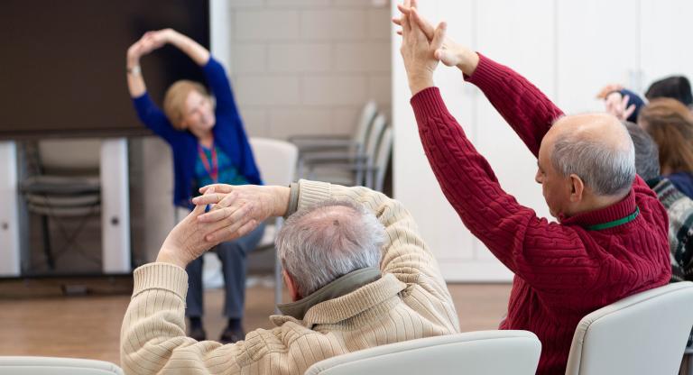 Older people stretching lead by an instructor