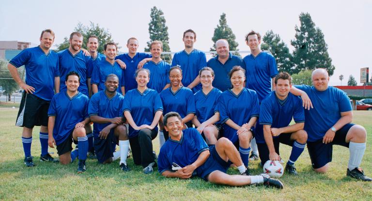 Corporate soccer team posing for a photo wearing blue jerseys