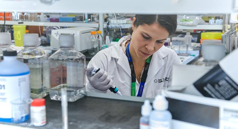 Female researcher working among various bottles and lab equipment 